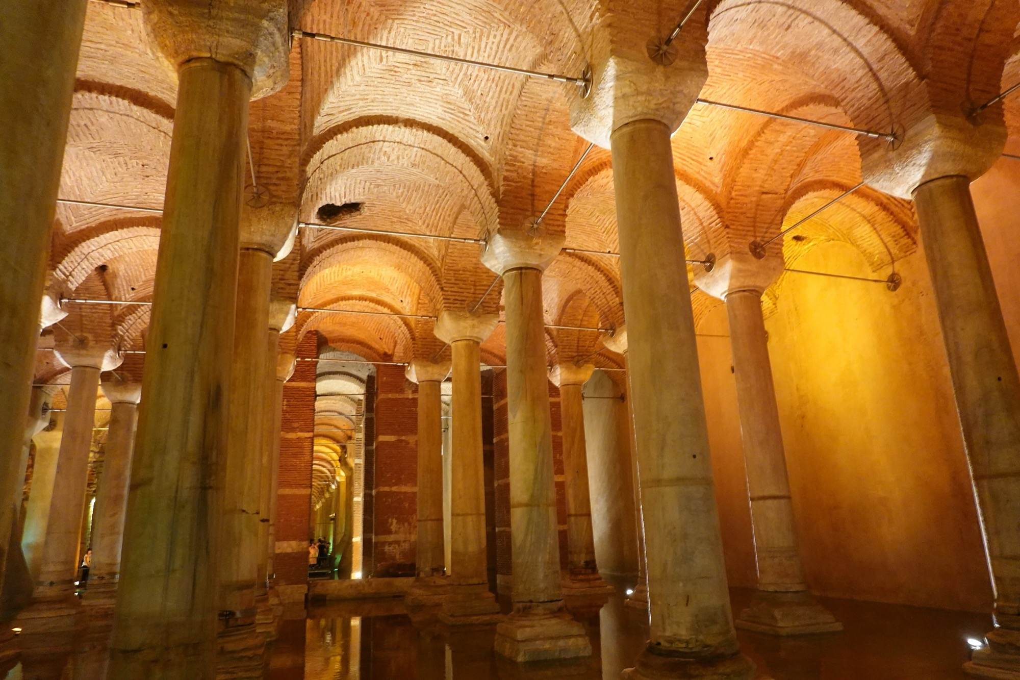 Hileras de columnas de mármol iluminadas en tonos cálidos bajo las bóvedas de ladrillo de la Cisterna Basílica